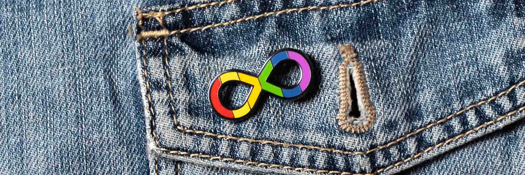 A rainbow infinity symbol pin on a denim jacket