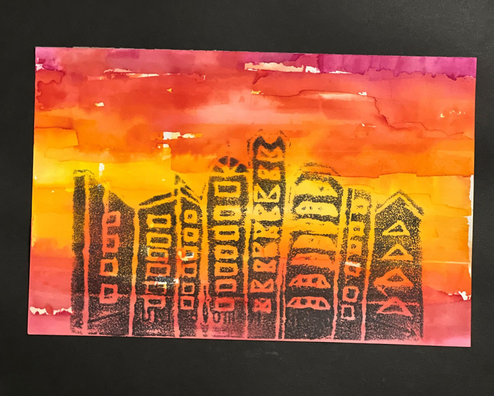 A child's art piece of a dark gray cityscape at sunset.