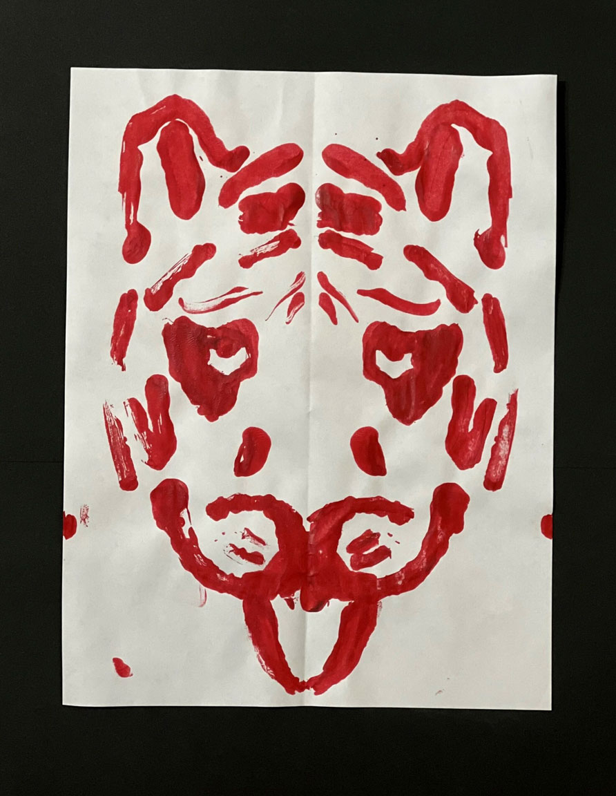 A child's painting of a tiger in red on a white piece of paper.