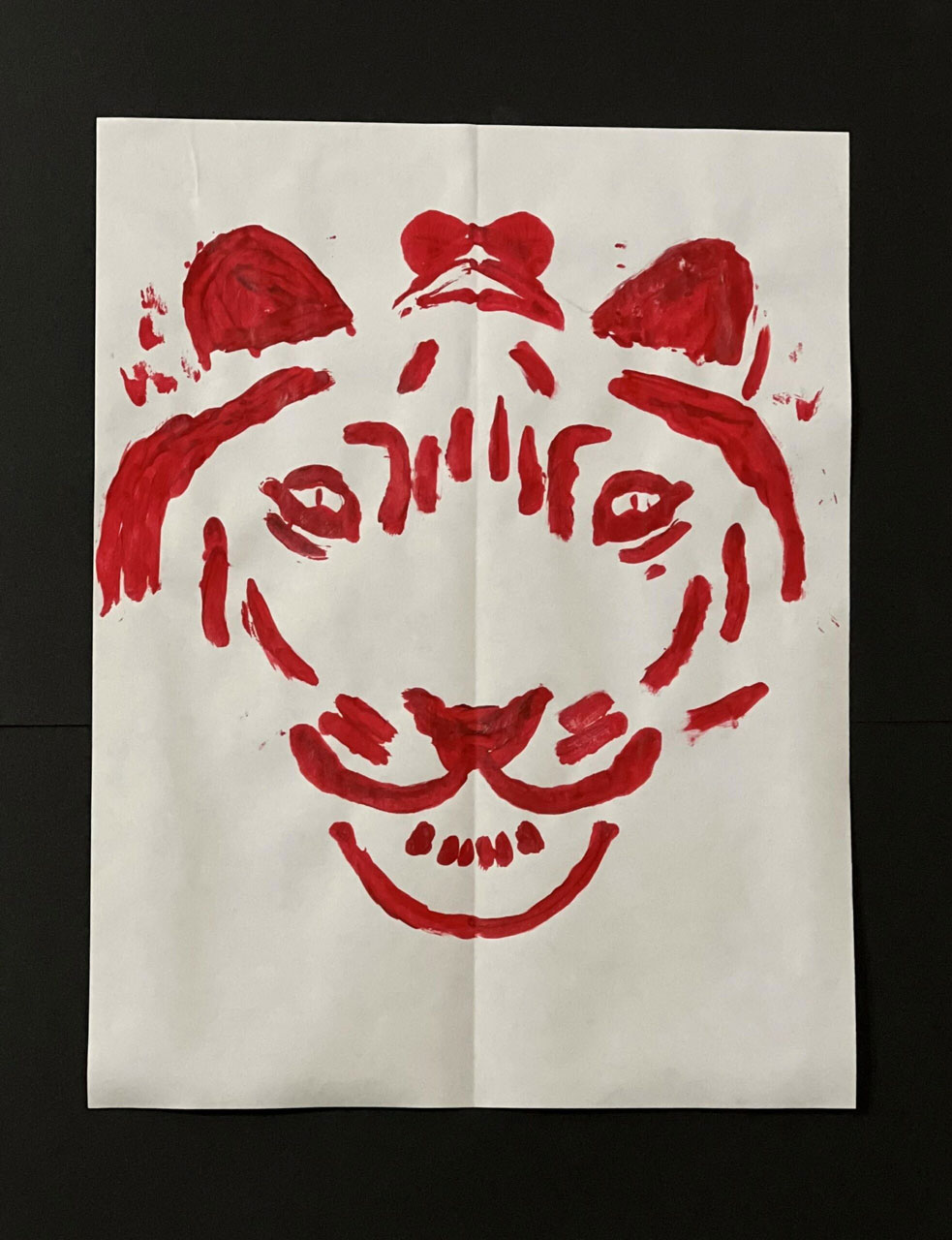 A painting of a tiger in red on a white piece of paper.