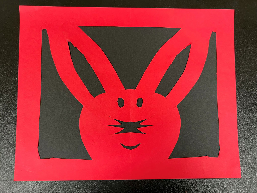 A child's red paper cutout of the head of a rabbit.