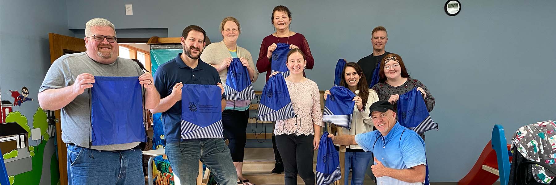 Members of the community and Kappa, Kappa, Kappa, inc holding blue string bags